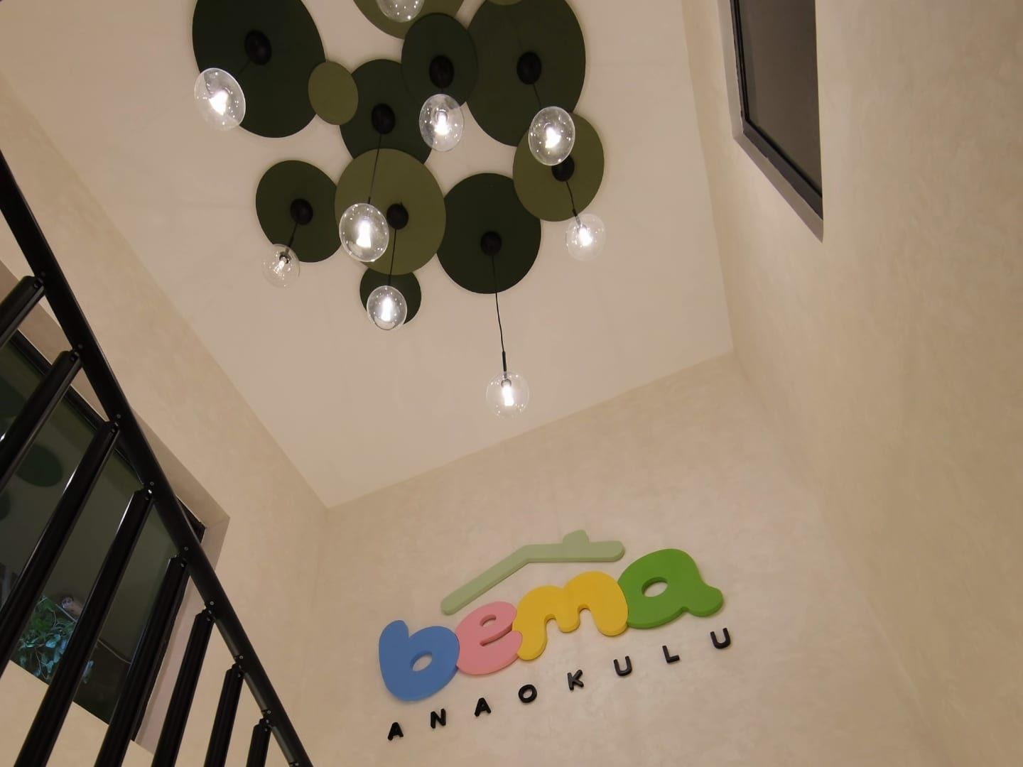 Yeşil daire aydınlatmalar ve BEMA logosuyla merdiven boşluğu
