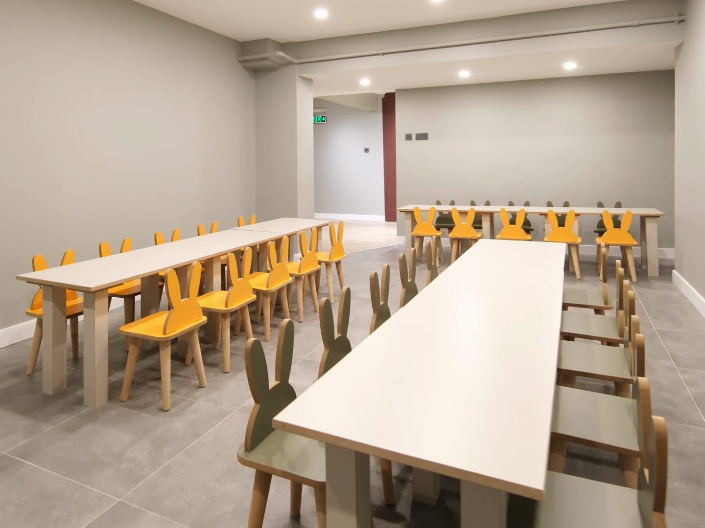 Yemekhanede uzun masalar ile sarı ve yeşil tavşan kulaklı çocuk sandalyeleri